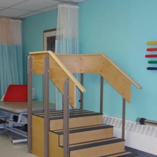 A physical therapy clinic featuring a set of wooden stairs used for rehabilitation exercises.