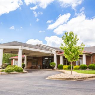 A welcoming hotel entrance with lush landscaping and a clear blue sky.