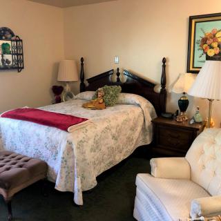 A cozy bedroom with a wooden bed, upholstered chair, and elegant decor.