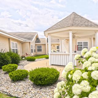 A peaceful garden with a gazebo surrounded by lush landscaping and blooming flowers.