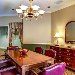 A well-furnished dining room with a wooden table, chairs, and elegant lighting.