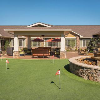 An outdoor view of a retirement home featuring a putting green and patio.