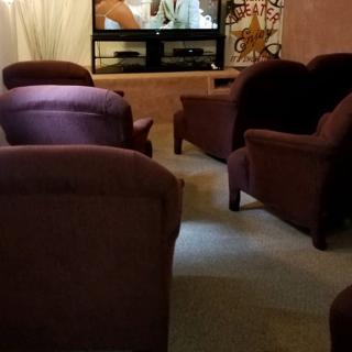 A cozy home theater setup with plush seating and a television screen.