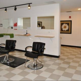 A modern hair salon with empty styling stations and sleek black chairs.