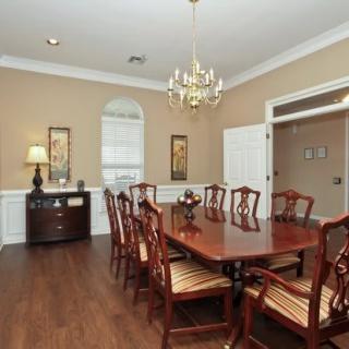 A traditional dining room with a large wooden table, matching chairs, and a chandelier.
