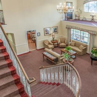 A spacious living room with a grand staircase and elegant chandelier.