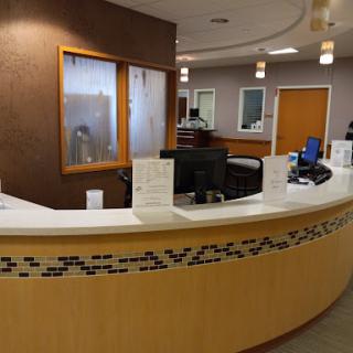 A modern reception area with a curved front desk, comfortable seating, and administrative space.