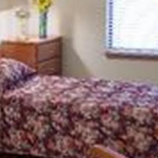 A cozy bedroom with a floral bedspread and a wooden dresser.