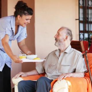 A caregiver assisting an elderly man with a meal at home.