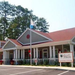 A building with a red roof and flagpole, surrounded by trees.