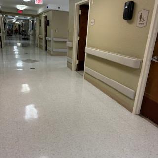 A quiet corridor in a hospital with doors leading to patient rooms.