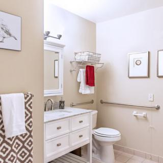 A neatly organized bathroom with a modern interior design, featuring a sink, toilet, mirror, and decorative wall art.