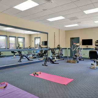 A spacious gym with exercise equipment and yoga mats, ready for a workout.