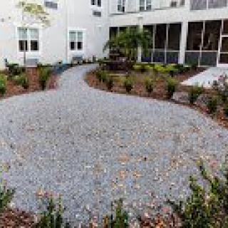 A landscaped garden with a gravel pathway surrounded by greenery and plants.