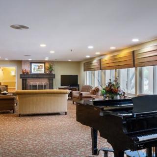A cozy living room with a grand piano, featuring comfortable seating and a fireplace.
