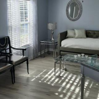A cozy living room with a daybed and elegant furnishings, illuminated by natural light through the window blinds.