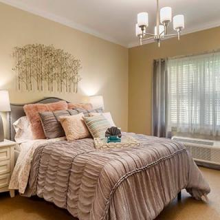 A cozy bedroom with elegant interior design, featuring a well-dressed bed, soft lighting, and tasteful decor.