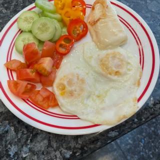 A colorful breakfast plate with fried eggs, toast, and fresh vegetables.