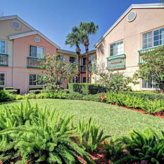 A picturesque residential building surrounded by lush greenery and palm trees.