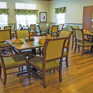 An elegant dining room with neatly arranged tables and chairs on a wooden floor.