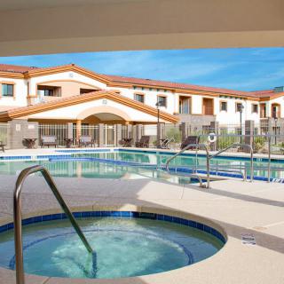 Outdoor view of a hotel with a swimming pool and hot tub under a clear blue sky.