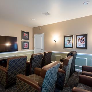 A cozy home theater room with comfortable armchairs, a large television, and decorative wall art.
