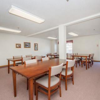 A spacious dining area featuring wooden tables and chairs, with bright lighting and simple decor.
