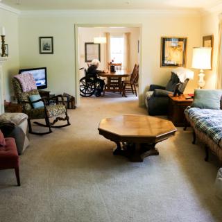 A cozy living room with various furniture pieces, including a wheelchair visible in the adjacent room.