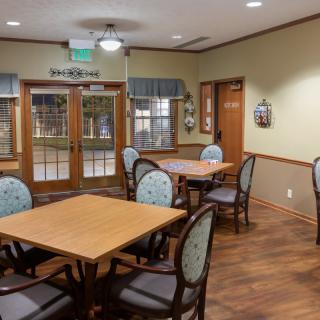 A cozy dining area with wooden tables and chairs, featuring a warm decor and ample natural light from the windows.