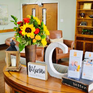 A warm and inviting reception area featuring vibrant flowers and a welcoming sign.