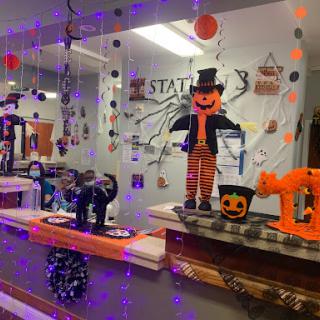 A festive Halloween-themed display featuring a scarecrow, black cat, and colorful decorations.