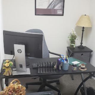A well-organized office workspace featuring a desk with a computer, lamp, and decorative items.