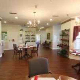 A cozy dining area with tables, chairs, and warm lighting on a hardwood floor.