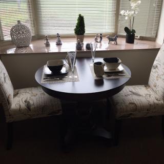 A cozy dining setup featuring a round table and stylish chairs, adorned with decorative elements.
