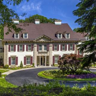 A luxurious mansion with beautiful landscaping and a circular driveway.