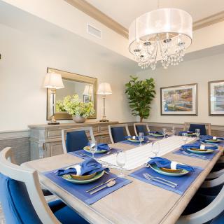 A beautifully set dining room table with blue and white decor, featuring a chandelier and elegant wall art.