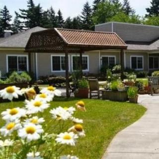 A serene outdoor view of a building surrounded by a garden with blooming flowers.