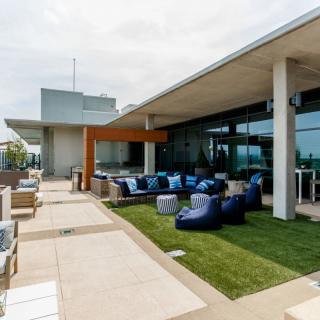 A modern rooftop terrace featuring comfortable bean bag seating and a small grass area.