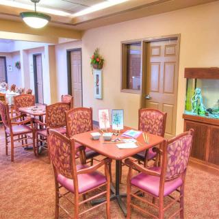 A cozy dining area with neatly arranged tables and chairs, featuring an aquarium and warm lighting.