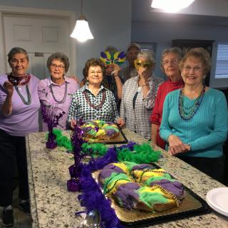 A group of people celebrating with colorful Mardi Gras cakes and decorations.