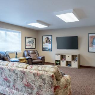 A cozy living room with a sofa and armchair facing a wall-mounted television.