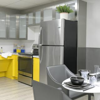 A contemporary kitchen featuring sleek stainless steel appliances and vibrant yellow accents, complete with a stylish dining area.