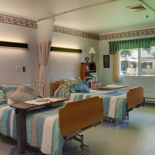A well-lit hospital patient room featuring two beds, designed for comfort and care.