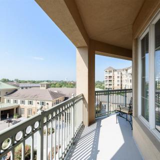 A spacious balcony with a view of surrounding buildings and a clear sky.