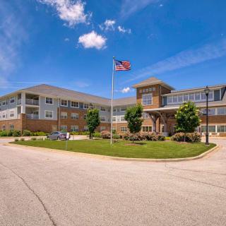 A modern building with an American flag flying in front, set against a partly cloudy sky.