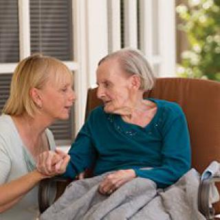 A caregiver and an elderly woman engaged in a heartfelt conversation outdoors.