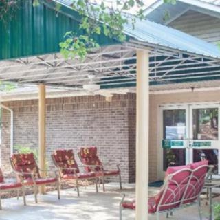 A cozy outdoor patio area with several cushioned chairs under a canopy in front of a brick building entrance.
