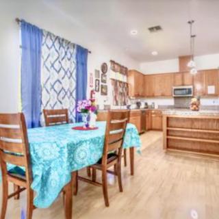 A modern kitchen and dining area with wooden furniture, blue curtains, and a turquoise tablecloth.