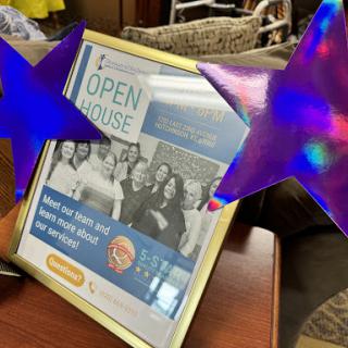 A festive display promoting an upcoming Open House event, featuring decorative stars and a framed advertisement.