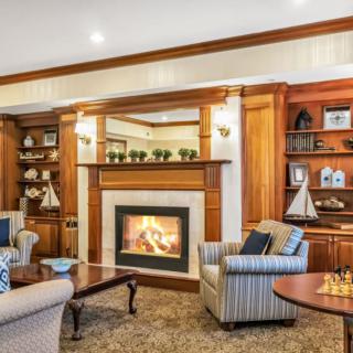 A cozy living room featuring a fireplace surrounded by elegant wooden bookshelves and comfortable armchairs.